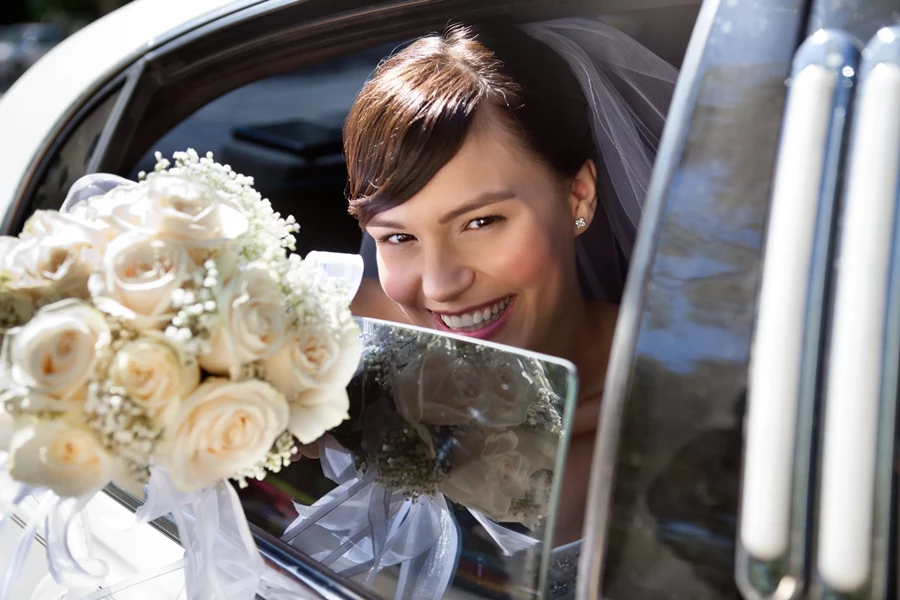 Bride looks happy in classic limo for her wedding day